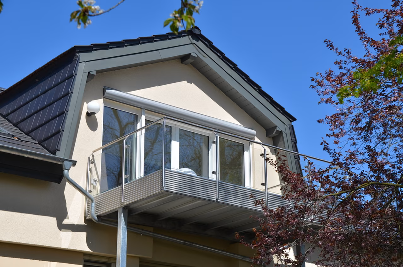 Gaube mit Balkon zwischen Bäumen