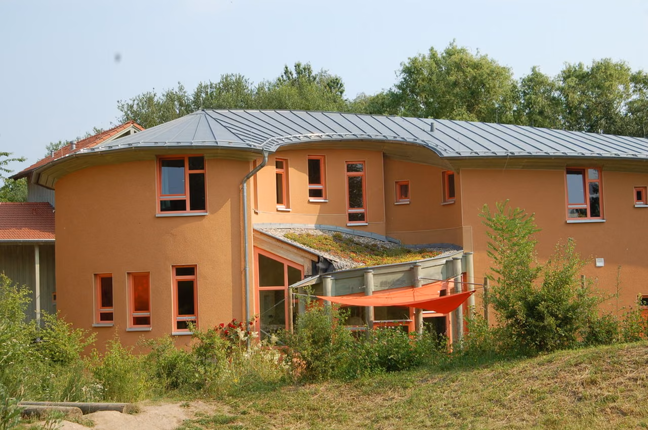 Rundbau mit ockerfarbener Fassade in einem naturnahen Garten