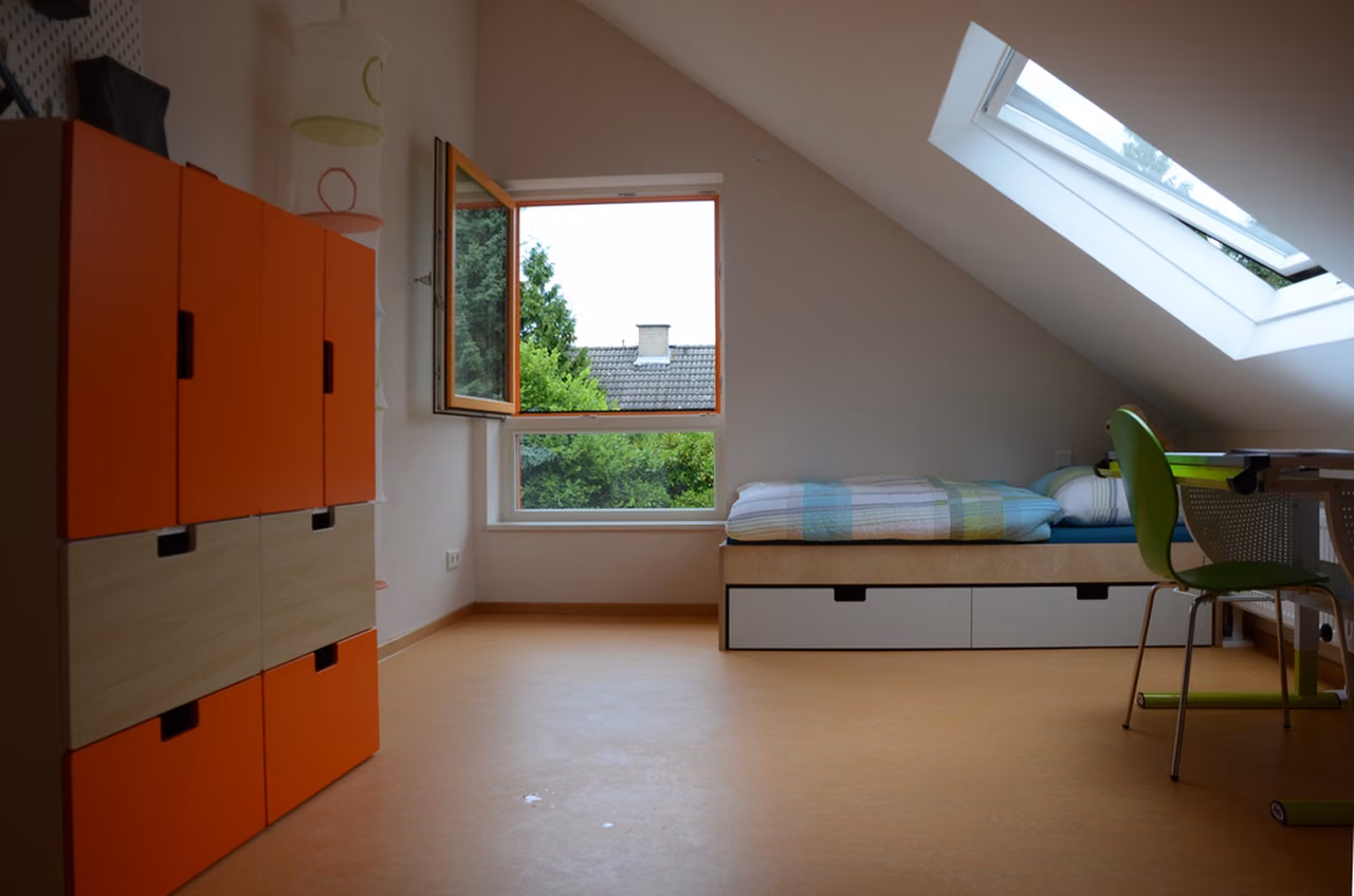 Kinderzimmer mit orangefarbenen Schränken und Dachfenster