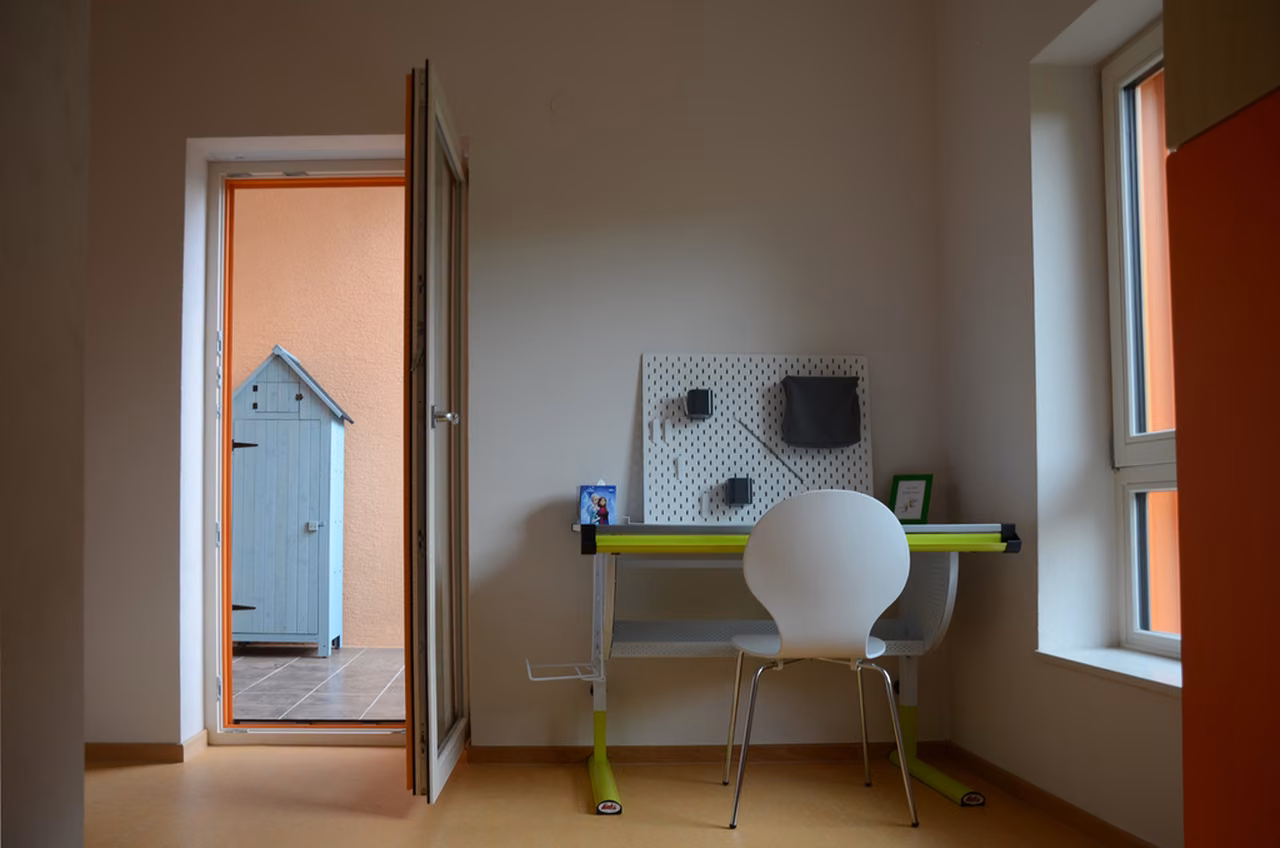Zimmer mit Schreibtisch und Wandtafel