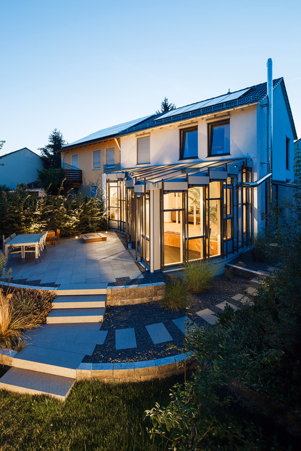 Gartenseite mit Wintergarten im Abendlicht