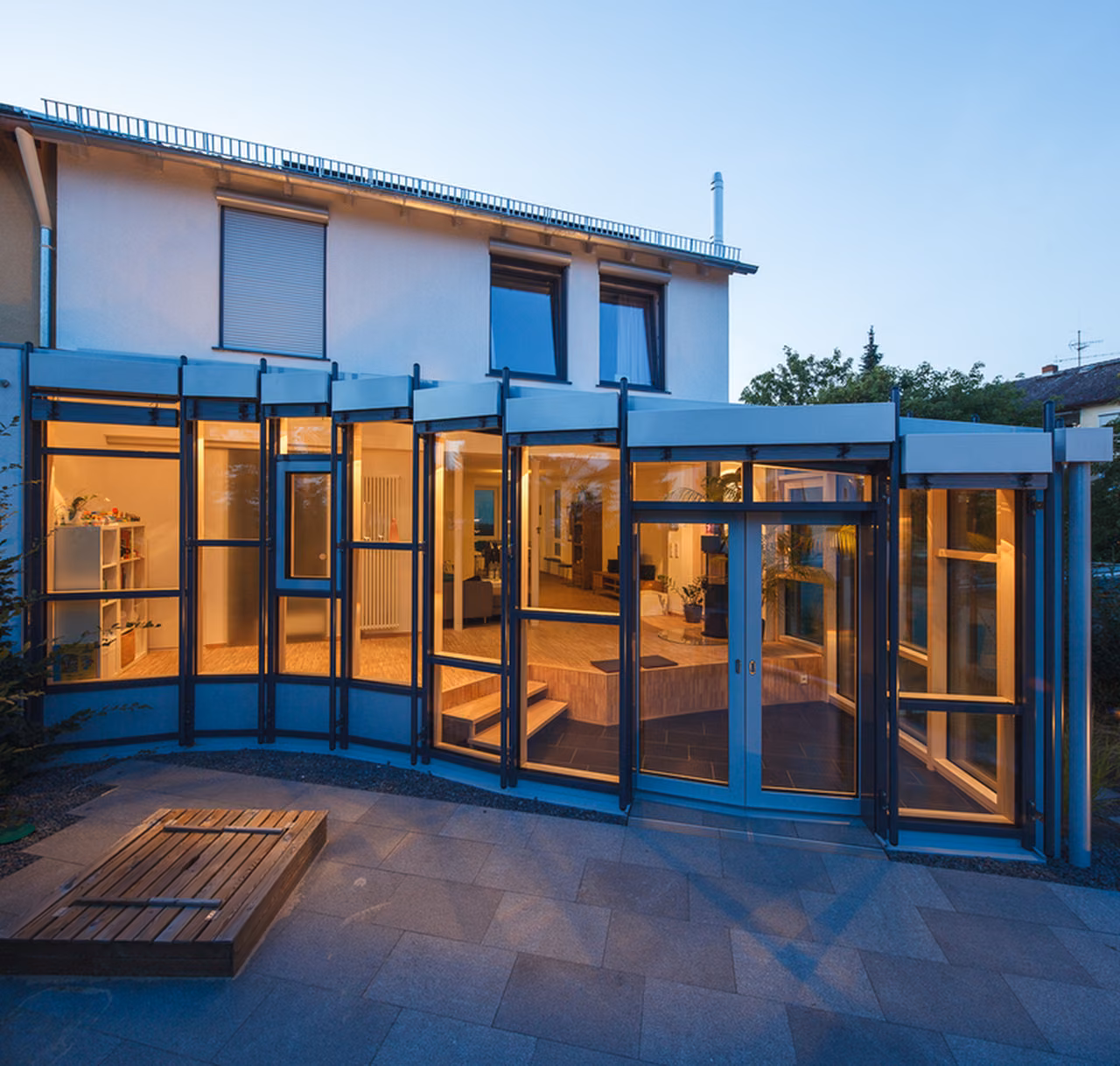 Gartenseite mit Glasanbau am Abend