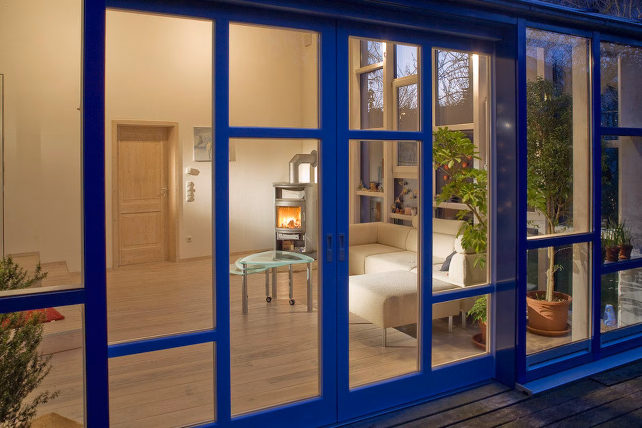 Blau gerahmte Glasfront mit Blick ins Wohnzimmer