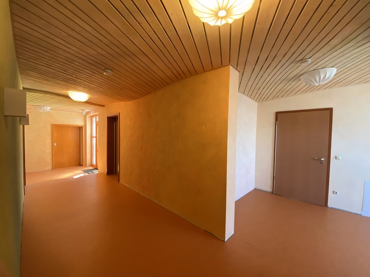 Flur mit Holzdecke und Türen in warmen Farben